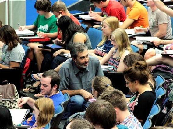 man in crowd of students in lecture hall teaching