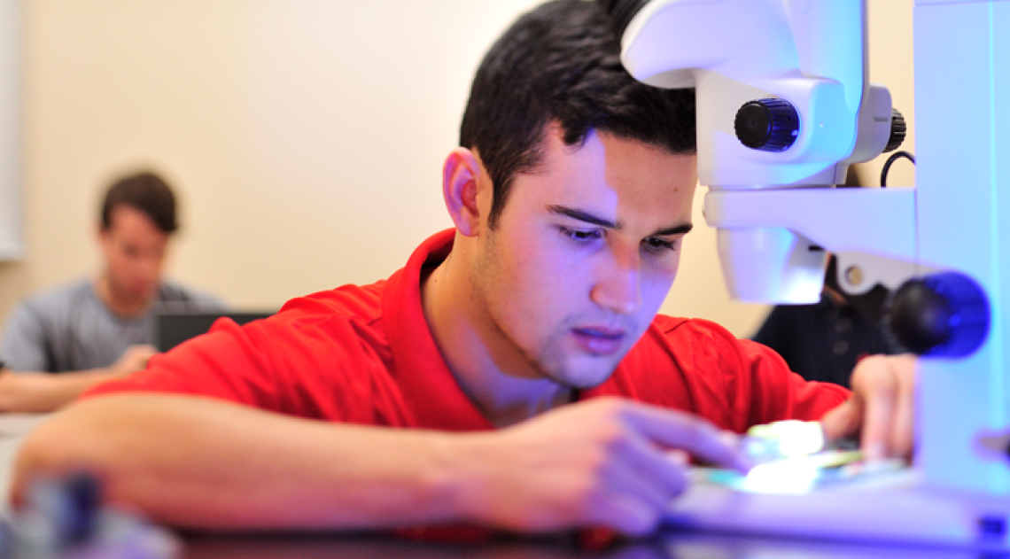 Male student working with a microscope