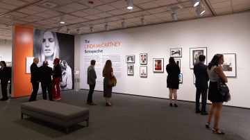 people standing and observing photographs hung on the wall
