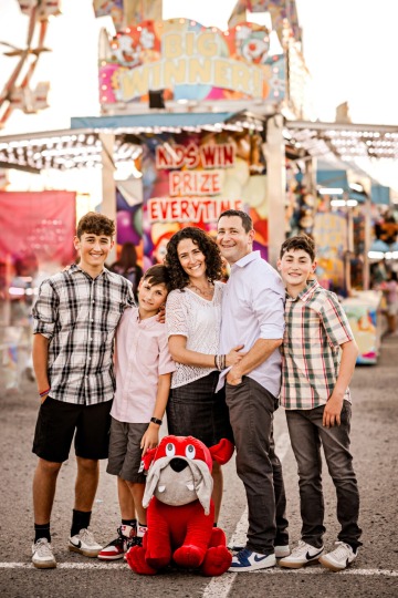 family of five people with carnival background